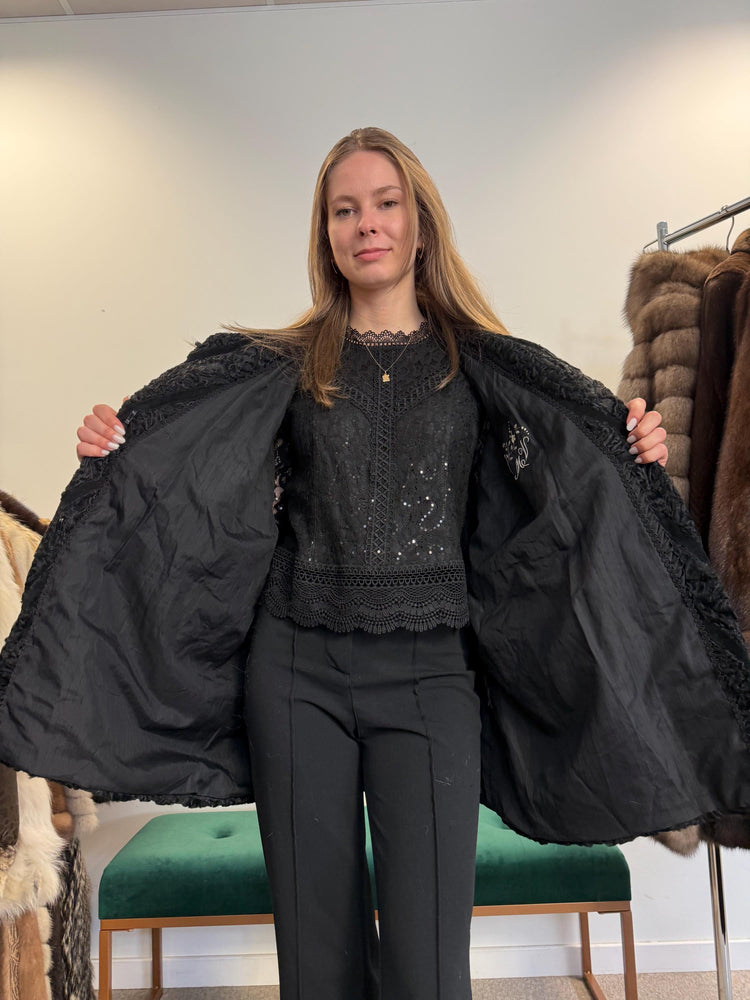 Black astrakhan fur vest, soft thick real fur, women’s, side view.